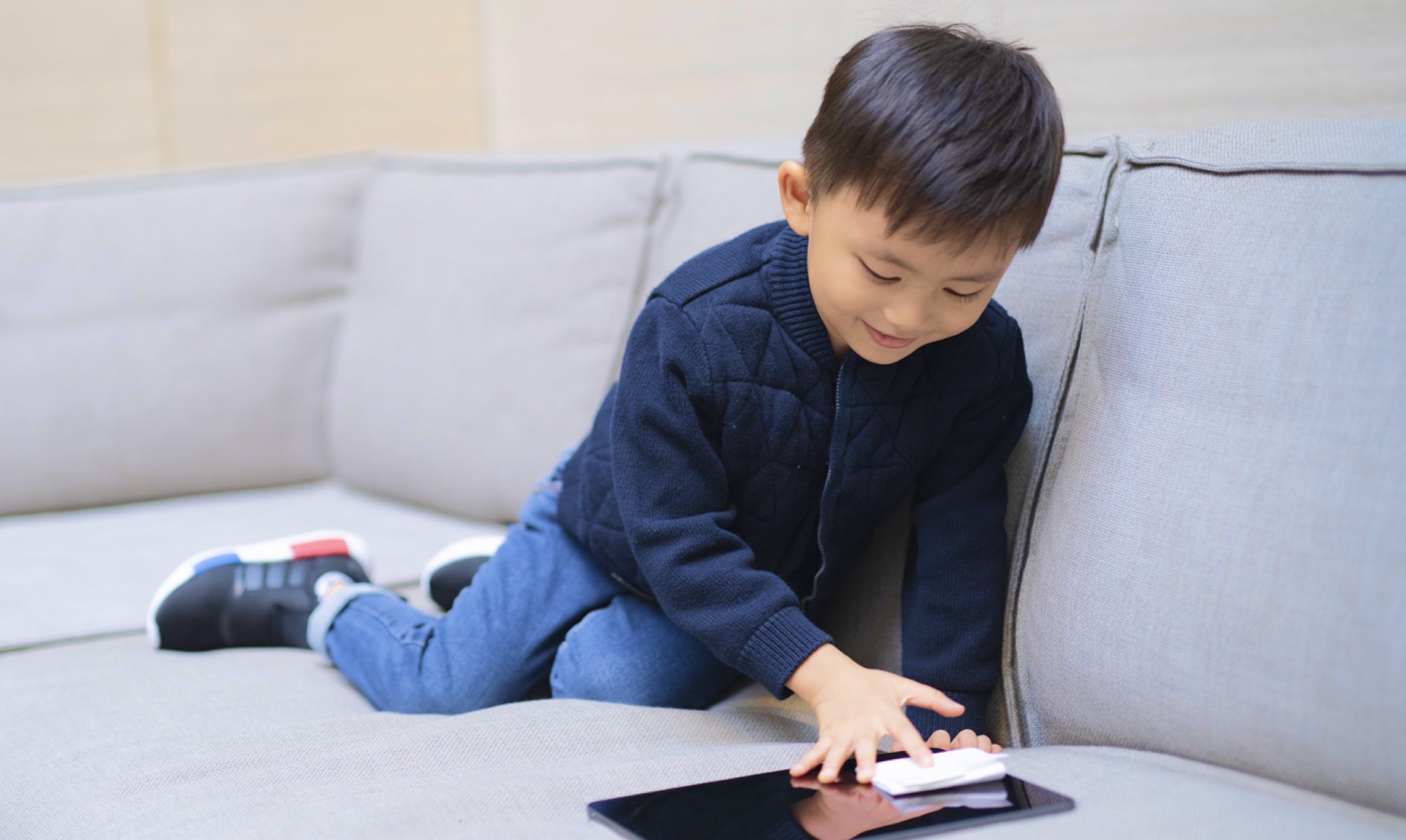 Young kid wiping his tablet with OVNU Personal Tech Wipes